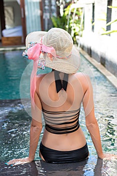 Young woman in swimsuit in swimming pool in gorgeous resort, luxury villa, tropical Bali island, Indonesia.