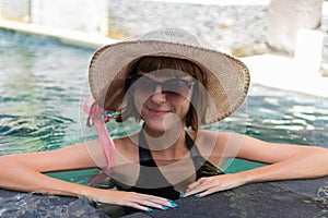 Young woman in swimsuit in swimming pool in gorgeous resort, luxury villa, tropical Bali island, Indonesia.