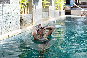 Young woman in swimsuit in swimming pool in gorgeous resort, luxury villa, tropical Bali island, Indonesia.