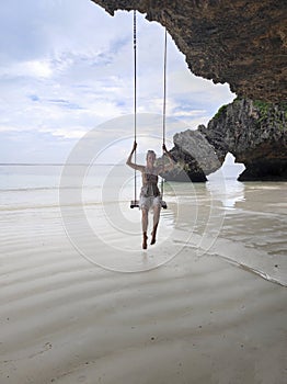 Young woman on a swing in beautiful Mtende beach Zanzibar