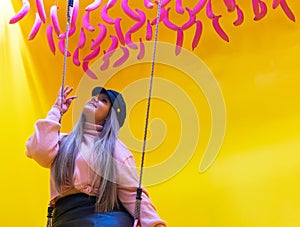 Young woman on swing with yellow background