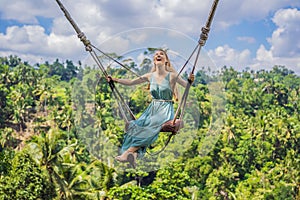 Young woman swinging in the jungle rainforest of Bali island, Indonesia. Swing in the tropics. Swings - trend of Bali