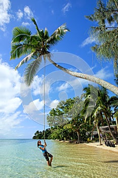 Young woman swinging on a rope swing at Pangaimotu island near T