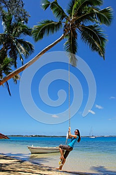 Young woman swinging on a rope swing at Pangaimotu island near T