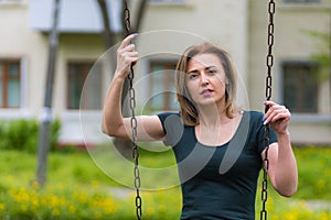 Young woman swinging on swing in the park with copy space. Freedom and happiness concept
