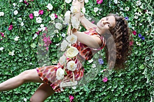 Young woman swings on swing overgrown with flowers