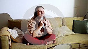 Young woman switch at living room. Home vacation sofa portrait. Watch tv video. Alone