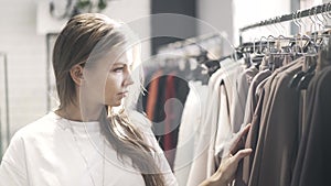 Young woman in a T shirt is choosing clothes in a store