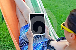 Young woman with a tablet computer in a hammock.