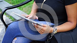 Young woman with tablet computer sitting in city park