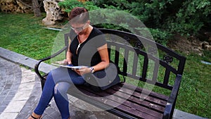 Young woman with tablet computer sitting in city park