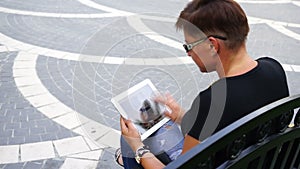 Young woman with tablet computer sitting in city park