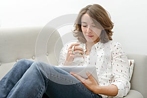 Young woman with a tablet drinks a cup of tea