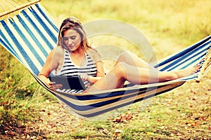 Young woman with tablet on the hammock