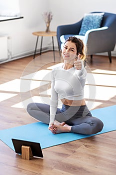 young woman with tablet pc doing yoga at home