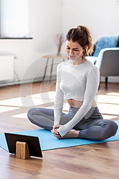 young woman with tablet pc doing yoga at home