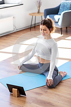 young woman with tablet pc doing yoga at home