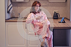 Young woman with a tablet and phone in her own kitchen. Work from home during quarantine and isolation due to the coronavirus