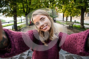 Young woman take selfie from hands with phone on summer city street