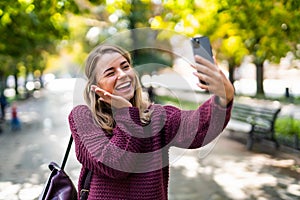 Young woman take selfie from hands with phone on summer city street. Urban life concept