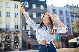 Young woman take selfie from hands with phone on summer city street. Urban life concept