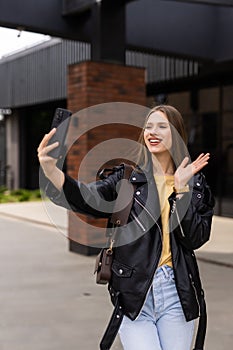 Young woman take selfie from hands with phone on summer city street. Urban life concept