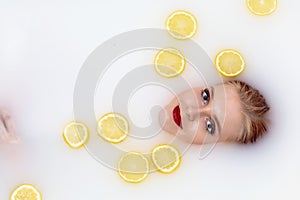 Young woman takes a bath with milk and citrus fruits