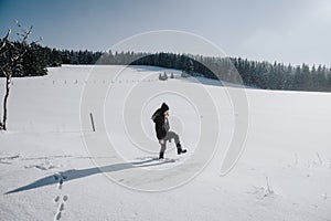 Young woman takes big steps in the deep snow of a field covered in snow