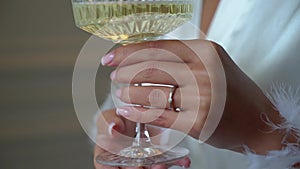 Young woman takes and hold crystal glass with sparkling white wine.