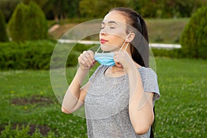 Young woman takes off medical mask and breath deeply with closed eyes.
