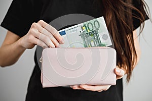 Young woman takes out money euro banknotes from a leather wallet. Close up