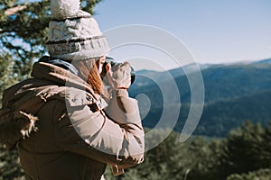 Young woman takes a photograph to the mountains