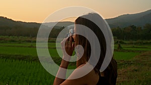 Young woman takes photos 0f the rice fields at sunset