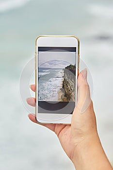 Young woman takes pictures on her phone. Girl taking pictures of a landscape.