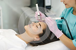 Young woman taking beauty procedure in spa salon. Electrophoresis