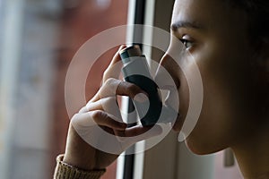 Young woman taking the blue asthma inhaler to treat an asthma attack photo