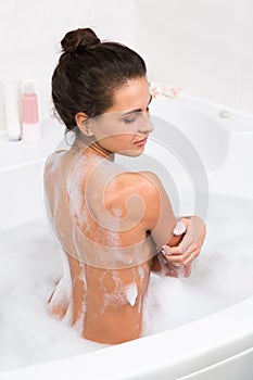 Young woman taking a bubble bath, rear view