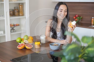 Young woman taking a nutritional supplement at breakfast