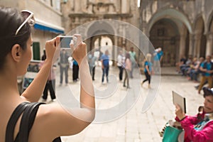 Young woman taking a photo with her smartphone. Woman tourist capturing memories. Tourist tour around city. Young woman tour