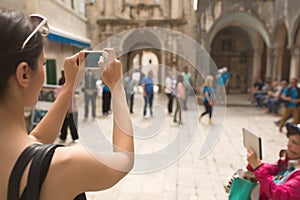 Young woman taking a photo with her smartphone. Woman tourist capturing memories. Tourist tour around city. Young woman tour photo