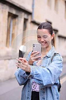 Young Woman Taking Photo Of Ice Cream Cone With Mobile Phone To Post On Social Media