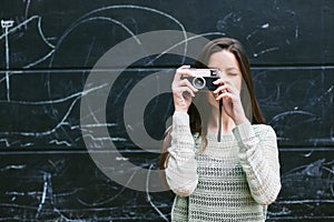 Young woman taking a photo with an old camera.
