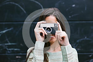 Young woman taking a photo with an old camera.
