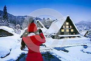 Young woman taking a photo at Shirakawa-go village in winter, UNESCO world heritage sites, Japan. photo