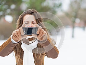 Young woman taking photo using cell phone in winter park