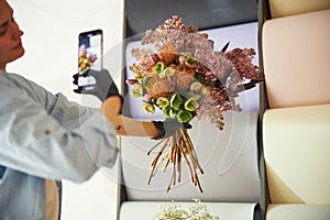 Young woman taking photos of a beautiful floral arrangement