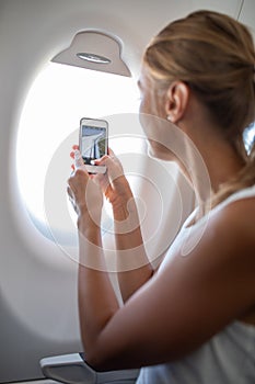 Young woman taking photos during flight