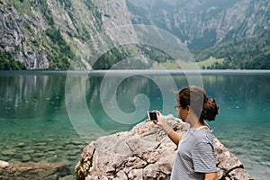 Young woman taking photos at beautiful and misty lake