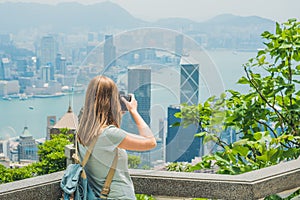 Young woman taking photos of victoria harbor in Hong Kong, China