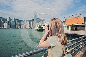 Young woman taking photos of victoria harbor in Hong Kong, China